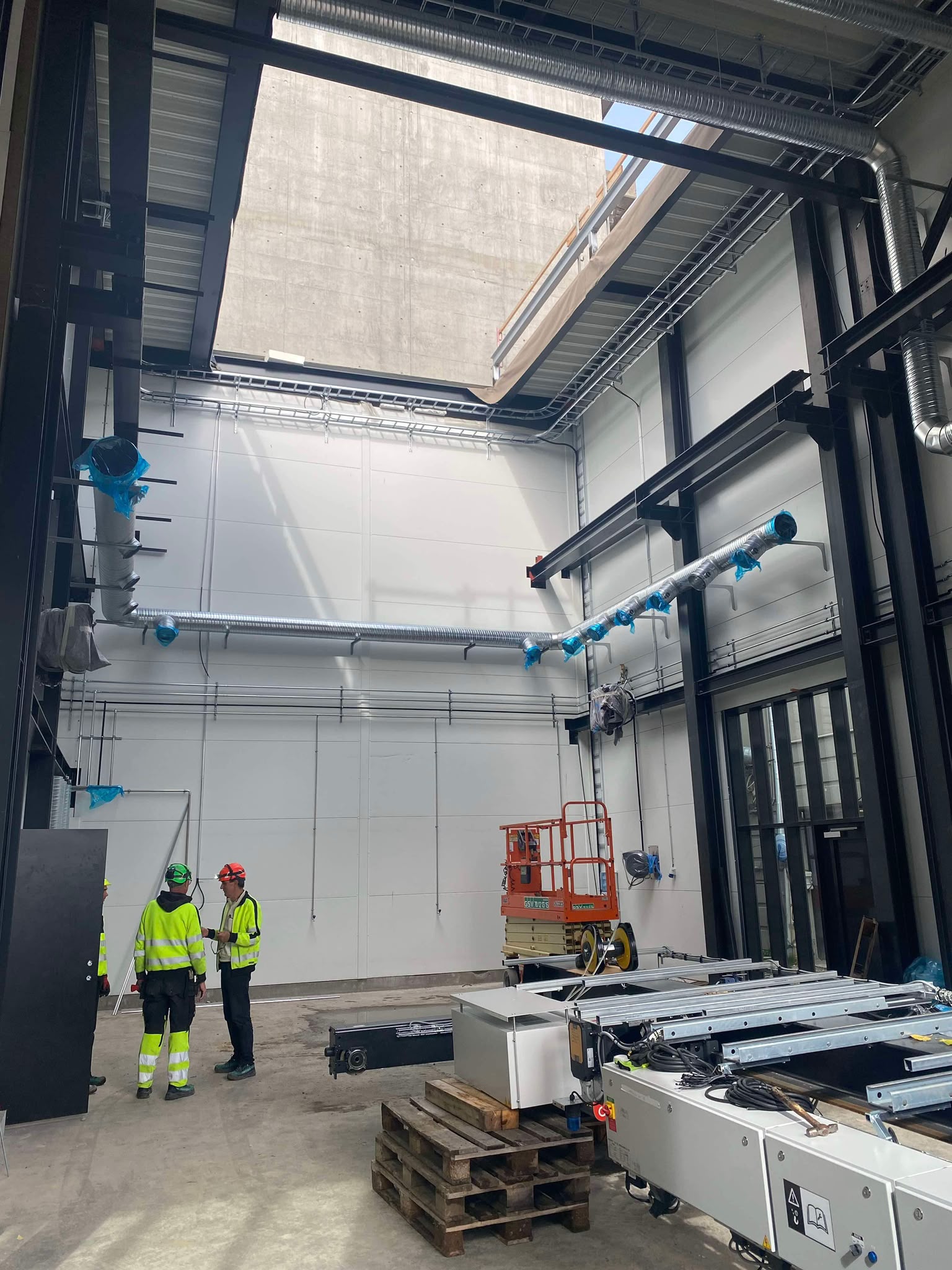 Medarbejdere i en hal med tekniske installationer under opførelse